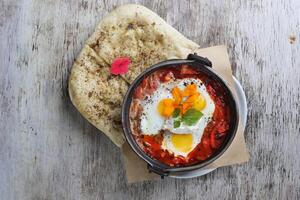 shakshuka con Pita pane servito nel piatto isolato su di legno sfondo superiore Visualizza di prima colazione foto