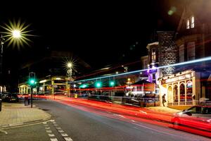 notte paesaggio urbano con leggero sentieri a partire dal in movimento veicoli su un' vivace strada, in mostra urbano vita notturna e movimento nel arrogante, nord yorkshire, UK. foto