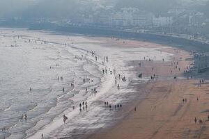aereo Visualizza di un' affollato spiaggia con onde e persone a piedi su il sabbia nel filey, Inghilterra. foto
