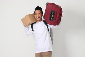 ritratto di eccitato asiatico musulmano uomo nel koko camicia con peci trasporto cartone scatola e Tenere valigia. andando casa per eid mubarak. isolato Immagine su bianca sfondo foto