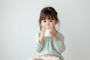 ai generato carino poco asiatico ragazza potabile latte su un' leggero sfondo foto