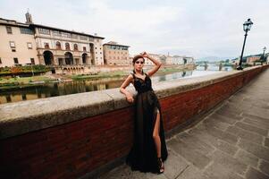 un' bellissimo elegante sposa nel un' nero vestito passeggiate attraverso Firenze, un' modello nel un' nero vestito nel il vecchio città di Italia foto