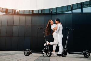 un' coppia su elettrico scooter abbraccio nel il città, un' coppia nel amore su scooter foto