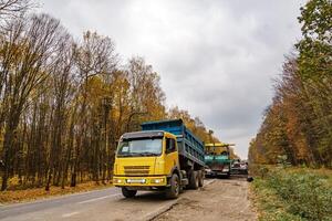 strada riparazione. posa nuovo asfalto. pesante speciale macchine. camion nel operazione. lato Visualizza. avvicinamento. foto