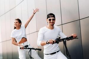 un' ragazza e un' tipo siamo a piedi su elettrico scooter in giro il città, un' coppia nel amore su scooter. foto