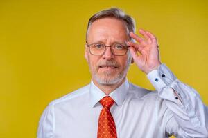 ritratto di un vecchio uomo sorridente, guardare a telecamera, nel studio, giallo sfondi uomo nel bicchieri ritratto foto