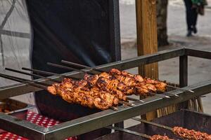 grigliato pollo spiedini su un all'aperto barbecue griglia con un' sfocato strada sfondo. foto