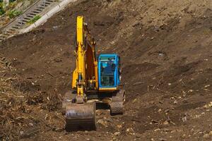 retroescavatore giallo con braccio del pistone idraulico contro il cielo blu chiaro. macchina pesante per scavi in cantiere. macchine idrauliche. enorme bulldozer. industria delle macchine pesanti. industria meccanica. foto