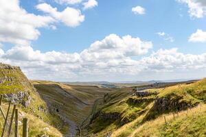 panoramico Visualizza di un' lussureggiante verde valle con rotolamento colline sotto un' blu cielo con soffice nuvole a malham baia, yorkshire, UK. foto