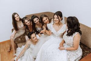 ritratto di il sposa con sua gli amici. elegante e elegante sposa con sua amici nel accoppiamento vestiti nel il camera nel il mattina. molti bellissimo ragazze nel uno foto. foto