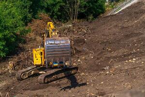 retroescavatore giallo con braccio del pistone idraulico contro il cielo blu chiaro. macchina pesante per scavi in cantiere. macchine idrauliche. enorme bulldozer. industria delle macchine pesanti. industria meccanica. foto