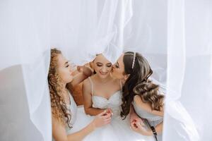 ritratto di il sposa con sua gli amici. elegante e elegante sposa con sua amici nel accoppiamento vestiti nel il camera nel il mattina. molti bellissimo ragazze nel uno foto. foto