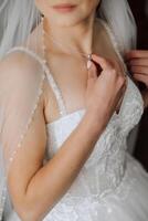 il sposa tocchi il pendente su sua collo con sua dita. preparazione per il nozze. nozze celebrazione. foto