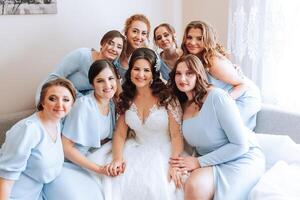 ritratto di il sposa con sua gli amici. elegante e elegante sposa con sua amici nel accoppiamento vestiti nel il camera nel il mattina. molti bellissimo ragazze nel uno foto. foto