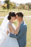 un' giovane sposa e sposo teneramente abbraccio nel il raggi di il autunno sole. tenero e bellissimo giovane ragazza sposa. un' uomo baci il suo Amati. contro il sfondo di un' bellissimo giardino foto