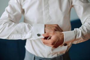 il uomo mettere su il suo camicia e si raddrizza gemelli. il sposo allacciare gemelli su il polsini di il camicia. il uomo d'affari allacciare gemelli su il polsini di il camicia. concetto riuscito uomo d'affari. foto