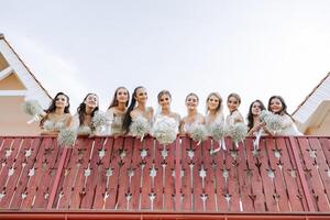 nozze foto sessione nel natura. il sposa e sua damigelle d'onore posa con mazzi di fiori