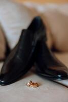 elegante nozze anelli su il sfondo di Uomini scarpe. promesse Fidanzamento. lusso matrimonio e nozze accessorio concetto. Due nozze anelli e un' nozze invito. foto