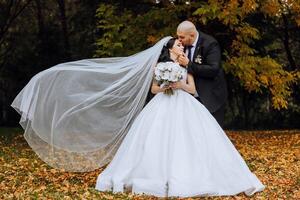 nozze coppia su un' camminare nel il autunno parco. il sposa nel un' bellissimo bianca vestire. amore e relazione concetto. sposo e sposa nel natura all'aperto foto