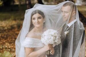 sono così lieto io sposato lui. ritagliata tiro di un affettuoso giovane sposa sorridente Abbracciare una persona sua sposo sotto un' velo su loro nozze giorno. foto