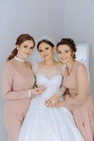 ritratto di il sposa con sua gli amici. elegante e elegante sposa con sua amici nel accoppiamento vestiti nel il camera nel il mattina. molti bellissimo ragazze nel uno foto. foto