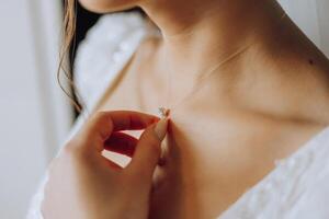 il sposa tocchi il pendente su sua collo con sua dita. preparazione per il nozze. nozze celebrazione. foto