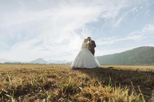 un' giovane sposa e sposo teneramente abbraccio nel il raggi di il autunno sole. tenero e bellissimo giovane ragazza sposa. un' uomo baci il suo Amati. contro il sfondo di un' bellissimo giardino foto