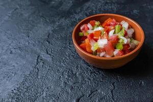 creolo salsa, fatto con campana peperoni, pomodori, cipolle nel un' ciotola su un' buio tavolo. foto