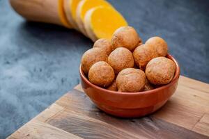 zucca frittelle. composizione dove il frittelle siamo nel un' ciotola su un' tavolo con il zucca su di messa a fuoco. foto