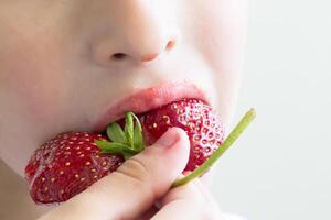 uomo mangia fragole. bacca nel il bocca. piccolo bambino o bambino mangiare rosso colore bacca di fragola foto