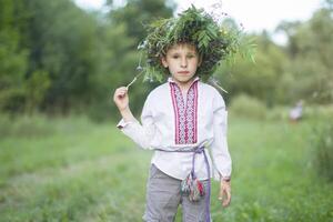 slavo bambino nel nazionale Abiti con un' ghirlanda su il suo testa. ucraino ragazzo. bielorusso a il festa di ivano kupala foto