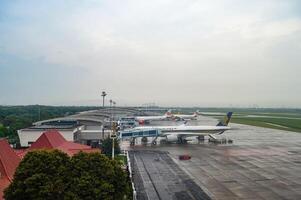 paesaggio di terminale 2 di Juanda internazionale aeroporto quale è attrezzata con un' moderno imbarco ponte con parecchi aerei parcheggiata su il grembiule, Indonesia, 6 gennaio 2024 foto
