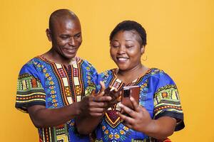 allegro africano americano coppia godendo sociale media Rete su mobile Telefono insieme. sorridente uomo e donna Sposa Guardando divertimento video e navigazione Internet su smartphone foto