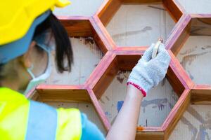 asiatico femmina lavoratore pittura di legno mobilia a un' lavoro luogo. foto