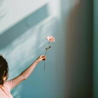 ai generato donna di mano con rosa gerbera su un' minimalista blu sfondo. fotografia con il concetto di bellezza e biologico cura foto