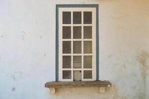 un' bianca in stile greco di legno finestra quello era in precedenza Usato come un' contatore nel un vecchio edificio quello è adesso no più a lungo Usato foto