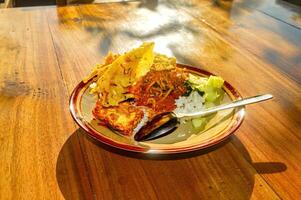 un' piatto di est giavanese madiun pecel riso su un' di legno tavolo nel il mattina luce del sole foto