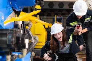 un' femmina lavoratore subìto un' gamba incidente mentre Lavorando nel robotica braccia fabbrica e maschio tecnico è porzione e fornire primo aiuto. foto