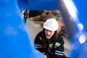 un' femmina lavoratore subìto un' gamba incidente mentre Lavorando nel robotica braccia fabbrica e maschio tecnico è porzione e fornire primo aiuto. foto