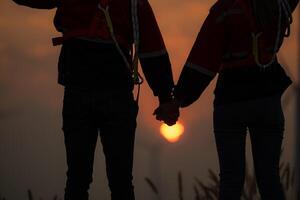 silhouette di un' uomo e donna Tenere mani su tramonto sfondo foto