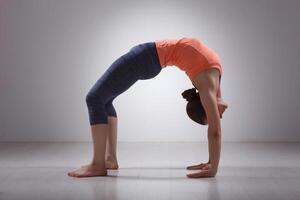 bellissimo sportivo in forma yogi ragazza pratiche yoga asana chakrasana foto