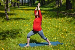 incinta donna fare asana virabhadrasana all'aperto foto