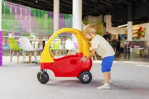 bambino piccolo con giocattolo auto a giocare la zona foto