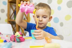 carino bambino seduta a il tavolo e giochi con plastilina foto