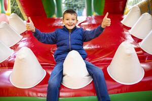 contento ragazzo avendo un' molte di divertimento su un' colorato gonfiare castello foto