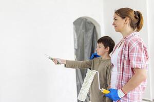 madre e bambino figlio dipingere il parete con dipingere utilizzando rullo e spazzola foto