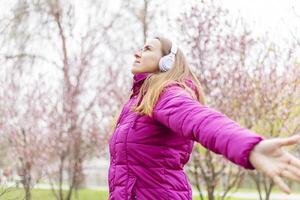 rilassato donna indossare cuffie respirazione fresco aria ascoltando per musica nel parco foto