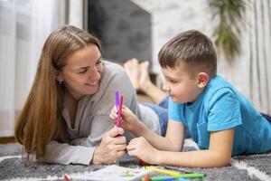 contento famiglia giocando insieme su pavimento. madre e figlio pittura insieme foto