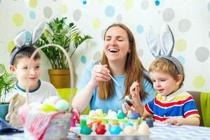 contento Pasqua. un' madre e sua bambini pittura Pasqua uova foto