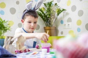 contento Pasqua. ragazzo nel coniglietto orecchie coloranti colorato uovo per Pasqua caccia foto